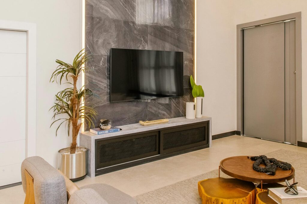 Flat-screen TV mounted on marble accent wall with LED backlighting in modern room