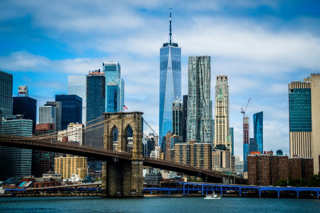Brooklyn Bridge spanning the East River with Lower Manhattan skyline and One World Trade Center in the background.
