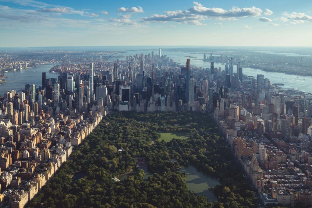 Aerial view of Central Park surrounded by Manhattan skyscrapers on a clear day.”