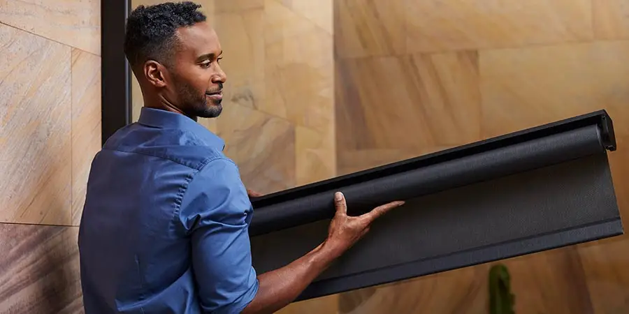 Persona sosteniendo un marco con malla negra enrollada, como una pantalla o mosquitero moderno listo para instalar.