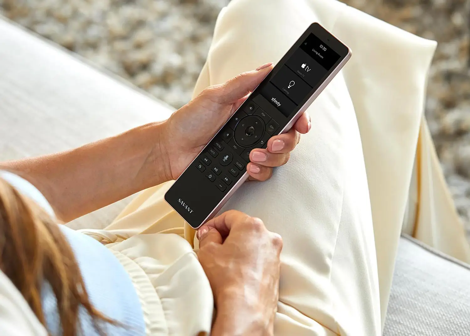 Remote control SAVANT moderno con pantalla táctil y botones físicos para controlar TV, iluminación y servicios como Apple TV y Xfinity.