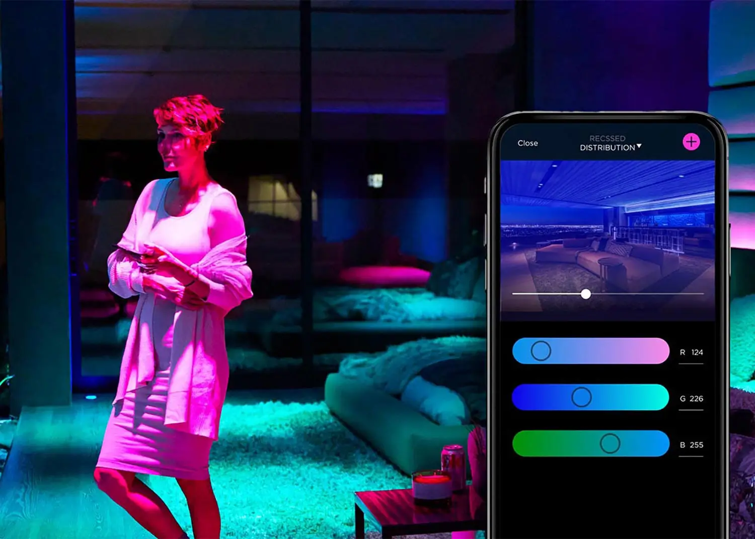 Person in a modern room filled with colorful ambient lighting, holding a smartphone that controls the RGB light settings shown on the screen.
